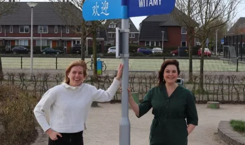 Martine (links) en Michelle (rechts) staan bij een wegwijzer met de tekst welkom in verschillende kleuren