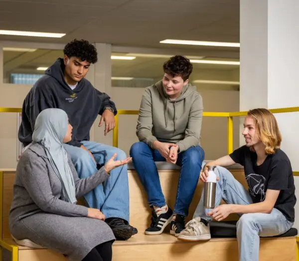 4 studenten zitten bij elkaar en zijn in gesprek