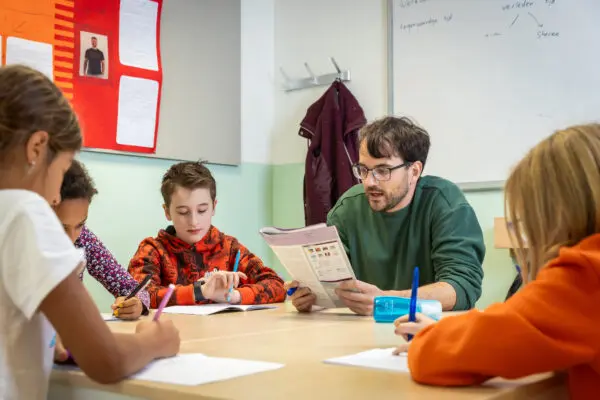 Basisschooldocent met leerlingen aan tafel