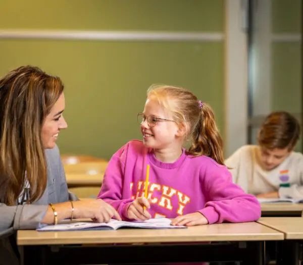 Docent helpt kind bij schoolwerk