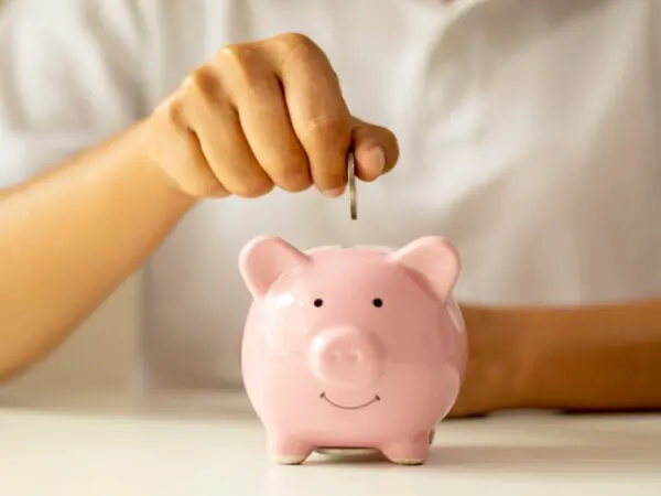 Hand doet een muntje in een varkensspaarpot