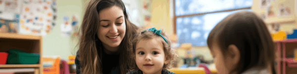 Een lerares met twee kleine kinderen die lachen naar de camera.