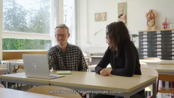 student en docent zitten naast elkaar achter laptop