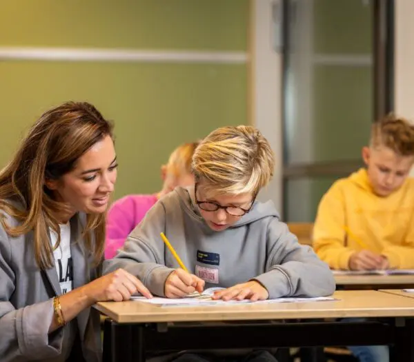 docent helpt leerling aan tafel