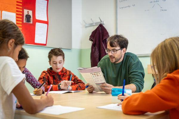 Basisschooldocent met leerlingen aan tafel