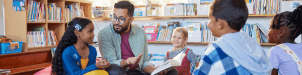 Een docent die vier leerlingen voorleest.