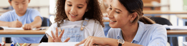 Lerares die een schoolopdracht uitlegt aan een leerling.