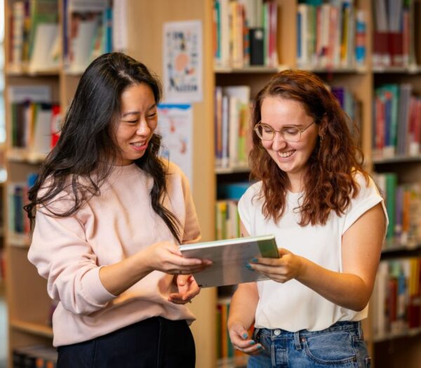 Student geeft een boek aan een andere student