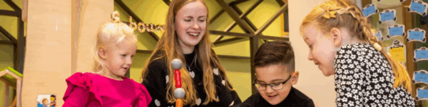 Drie kinderen die een toren bouwen samen met een leerkracht.