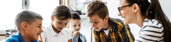 Leerkracht aan tafel met leerlingen.