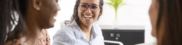 Drie vrouwen die samenwerken en lachen naar elkaar.