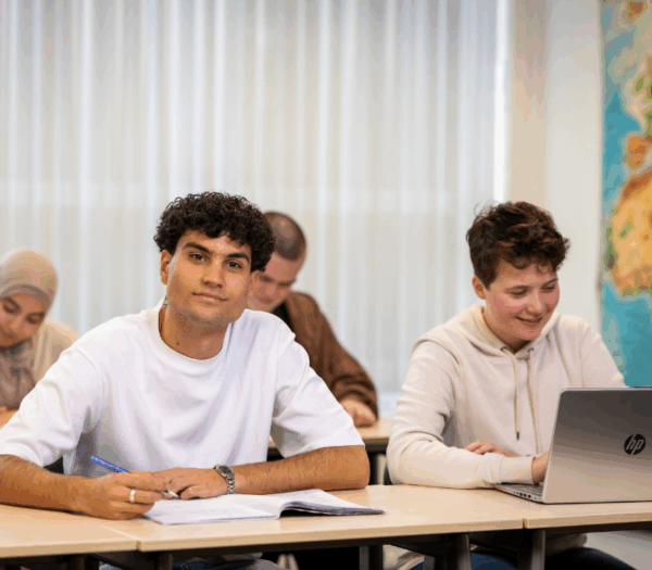 Studenten in klaslokaal, voorste student kijkt in de camera
