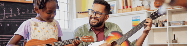 Een muziekdocent die samen met een leerling speelt op een gitaar.