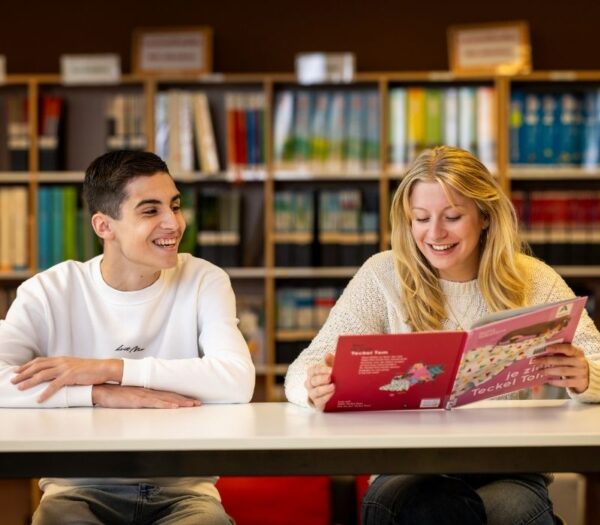 Twee studenten zitten naast elkaar en lezen een boek