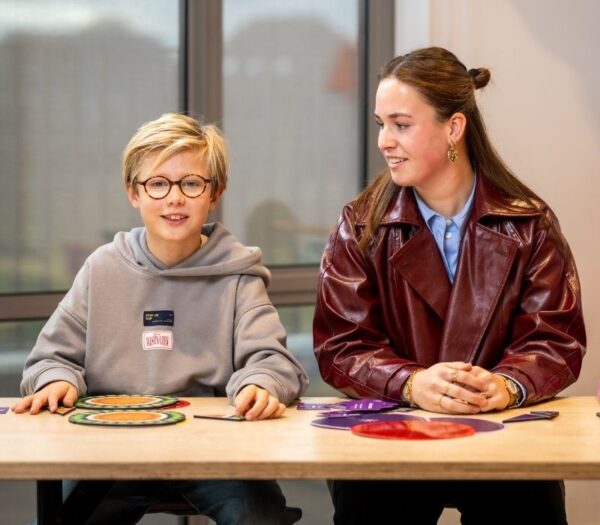 Pabo student en leerling zitten naast elkaar aan tafel