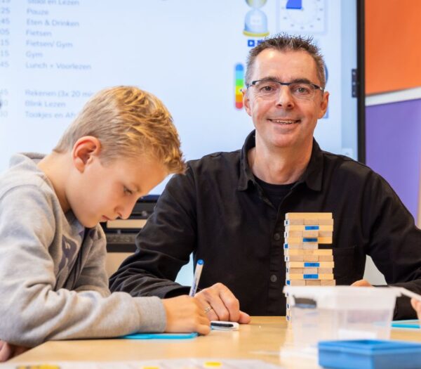 Docent zit met kind aan tafel
