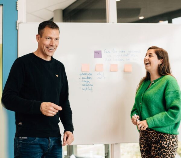 man en vrouw staan voor schoolbord