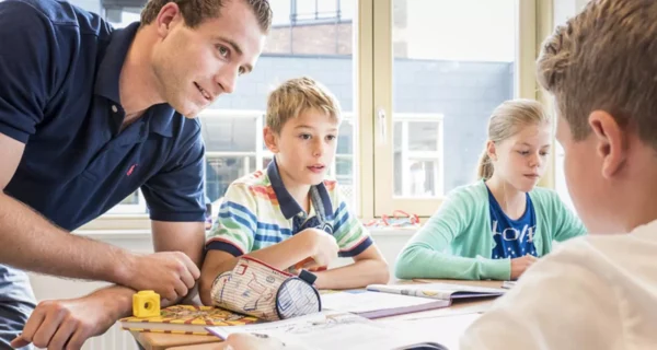 Een docent met drie kinderen aan tafel.