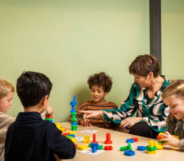 Docent speelt met leerlingen aan tafel