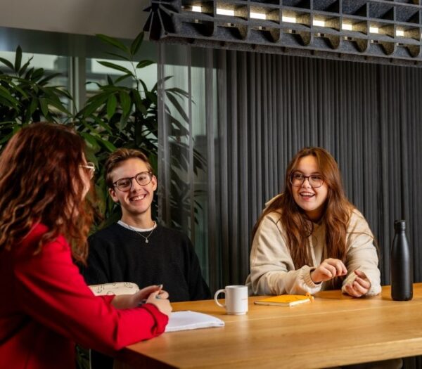 Drie studenten lachen met elkaar